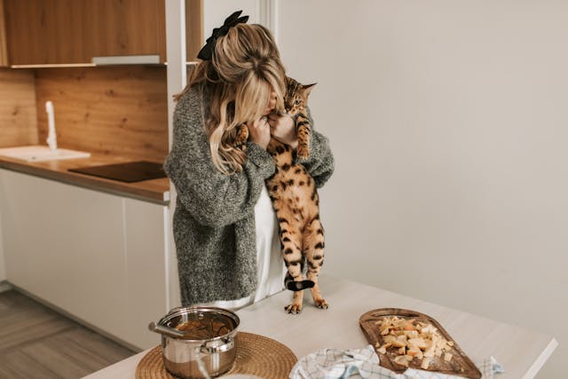 Woman wearing gray sweater holding a brown cat